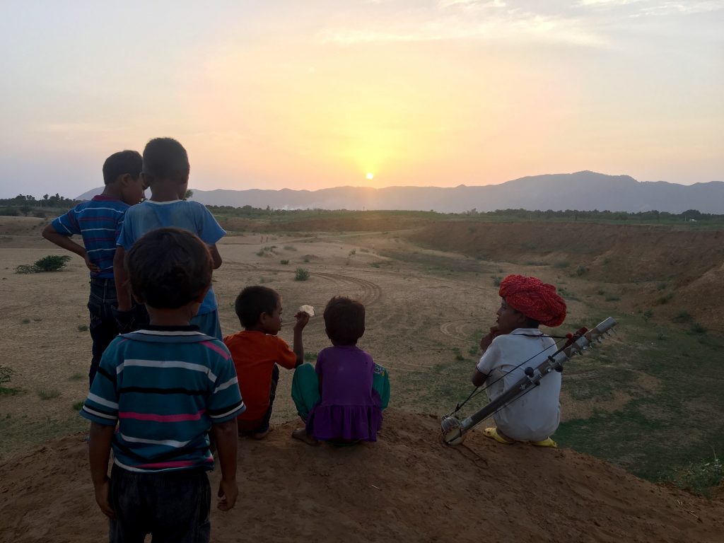 Kids watching the sunset over the sand dunes in Pushkar
