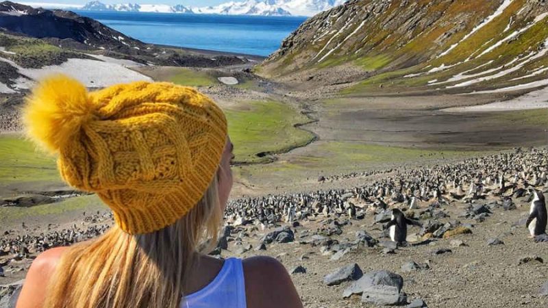 Adventure traveler being in the moment while watching penguins in Antarctica.